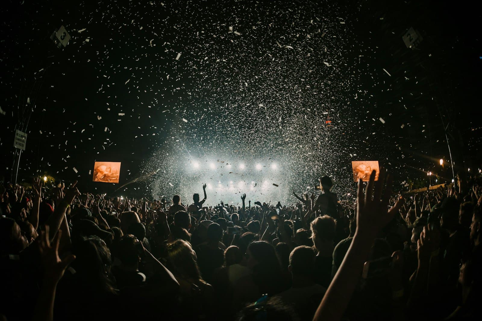 Festival crowd under confetti and stage lights at night