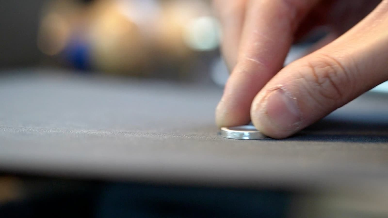 A silver ring set down on the jeweller's bench, tools blurred behind