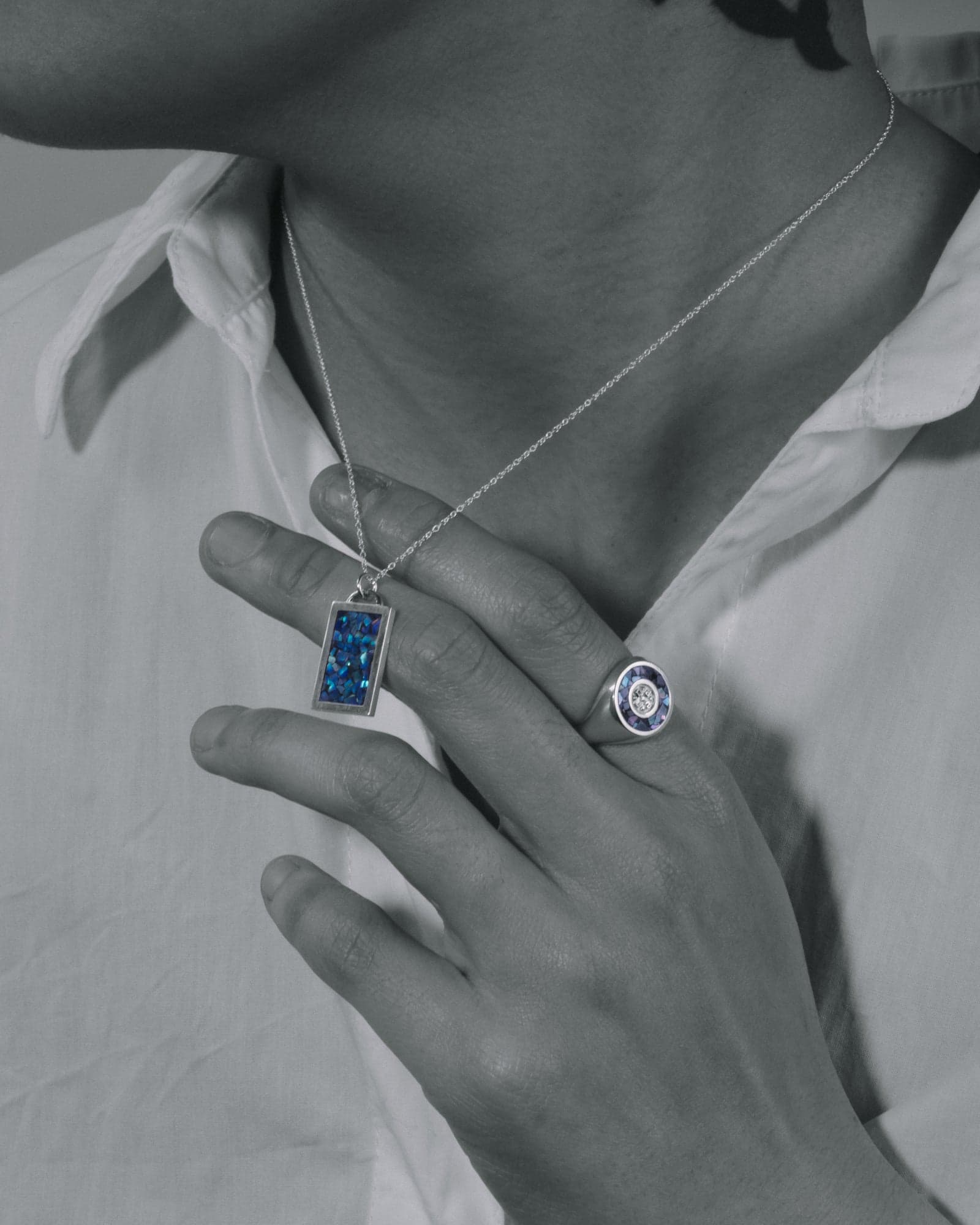 Black-and-white campaign shot with the pendant's blue inlay left in colour