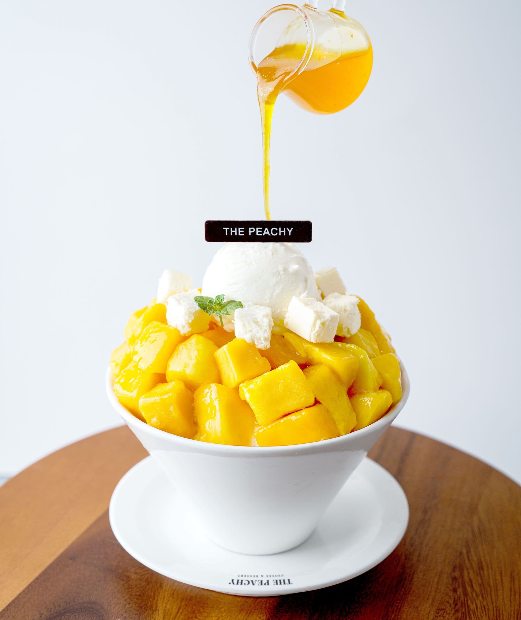 The Peachy apple mango bingsu with syrup being poured over it
